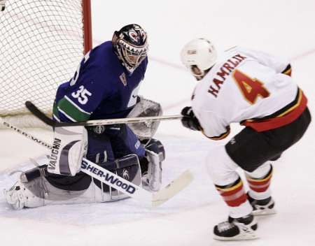 Roman Hamrlík z Calgary (v bílém) se marně snaží překonat vancouverského brankáře Alexe Aulda. | Foto: Reuters