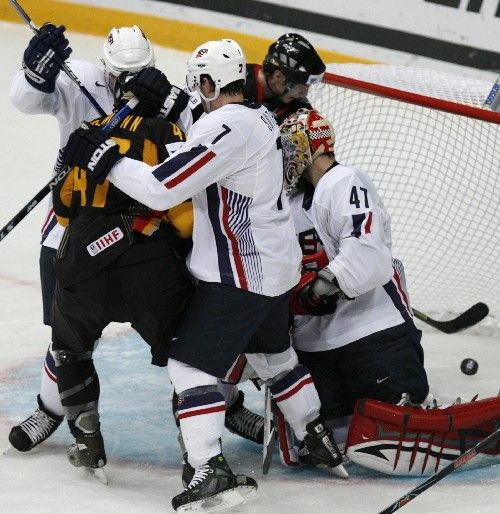 Německý hokejista Florian Busch (vzadu) sleduju puk, který propadl za záda americkému brankáři Johnu Grahamovi (47). | Foto: Reuters