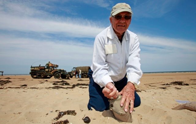 Americký válečný veterán Benza Getona sbírá písek na pláži ve Vierville-sur-Mer | Foto: Reuters