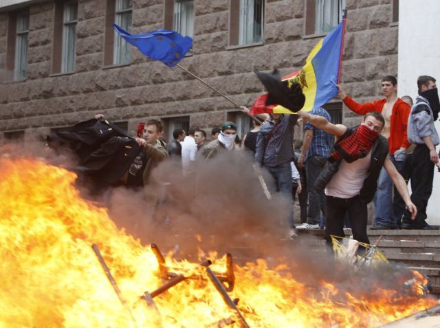 Studenti přihazují uniformy do zapáleného vybavení parlamentu. | Foto: Reuters