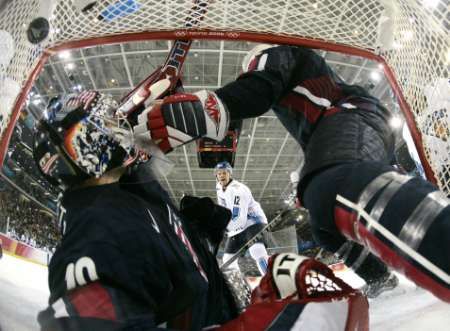 Olli Jokinen z Finska (v bílém) právě dává gól do sítě amerického gólmana Ricka Dipietra. Vpravo je obránce Jordan Leopold. | Foto: Reuters