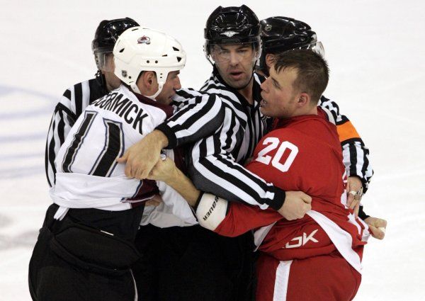 Muži v pruhovaném trhají od sebe útočníka Colorada Avalanche Cody McCormicka (vlevo) a útočníka Detroitu Red Wings Aarona Downeyho. | Foto: Reuters