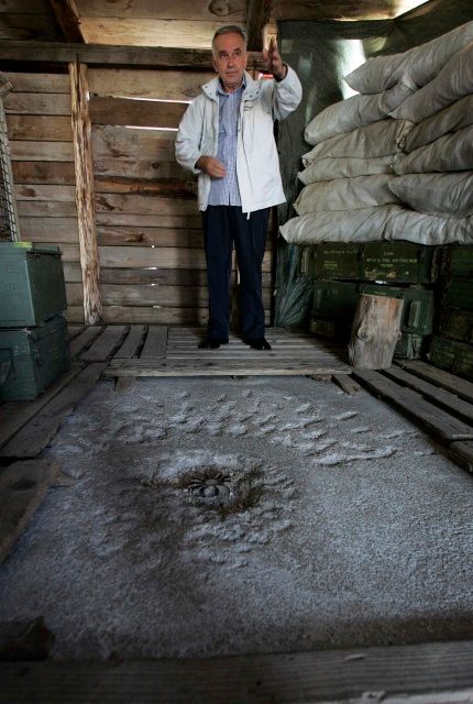 Bajro Kolar stojí za dírou, kterou vytvořil minometný granát | Foto: Reuters