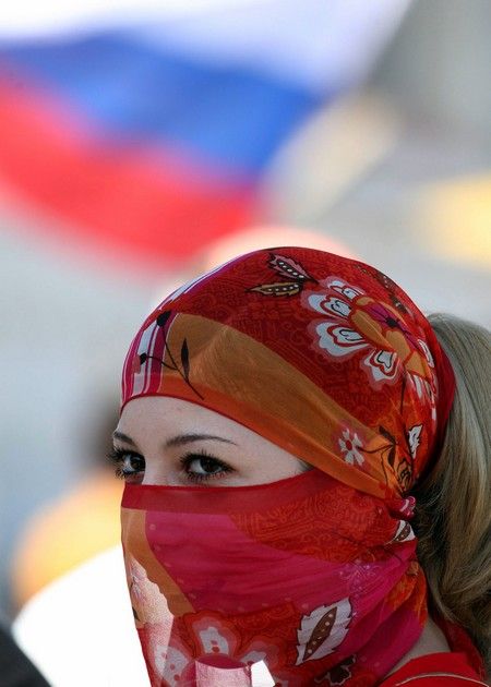 Mladá Čečenka stojí před ruskou vlajkou v hlavním městě Grozném. | Foto: REUTERS/Eduard Kornijenko