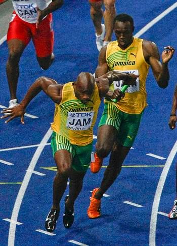 Usain Bolt předává finišmenovi Powellovi | Foto: Reuters