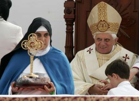 Řádová sestra drží relikviář s ostatky prvního brazilského světce Antónia Galvaa. Papež Benedikt XVI., který proces jeho kanonizace završil, přihlíží | Foto: Reuters