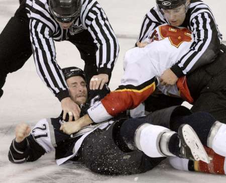 Čároví rozhodčí se od sebe snaží dostat Robyna Regerha z Calgary (vpravo) a edmontonského Jasona Smitha. | Foto: Reuters