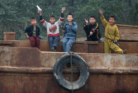 Kluci s pistolkami si hrají ve městě Sinujiu na severokorejské straně řeky Ja-lu, která odděluje Severní Koreu od Číny | Foto: REUTERS / Reinhard Krause