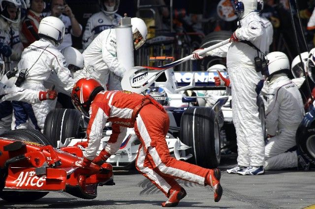 Kimi Räikkönen se snaží dostat své Ferrari do boxů, zatímco za ním mechanici BMW Sauberu pilně pracují na monopostu Nicka Heidfelda. | Foto: Reuters