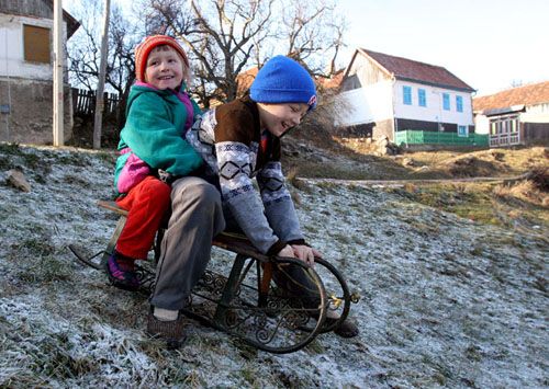 "Nýčko pojedu já s Mariánkou!" volají na sebe děti sáňkující na jinovatce ve vesnici Gernik, osm set kilometrů vzdálené od Prahy. Ani v rumunském Banátu, kde stále žije kolem dvou tisíc Čechů, sníh letos ještě pořádně nenapadl. Zítra se tyto děti i jejich rodiče stanou občany EU. | Foto: Ondřej Besperát