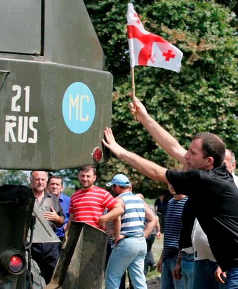 Gruzínec se snaží umístit vlajku své vlasti na projíždějící vozidlo ruské armády | Foto: Reuters