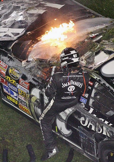 Jezdec série NASCAR Clint Bowyer ze souká ze svého hořícího vozu po havári v závodě Daytona 500. | Foto: Reuters