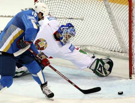 Běloruský gólman Andrej Mezin kryje pokus Konstantina Šafranova z Kazachstánu (v modrém). | Foto: Reuters