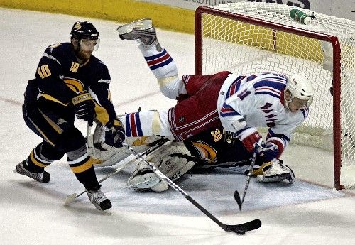 Útočník New Yorku Rangers Marcele Hossa (vpravo) padá přes gólmana Buffala Ryana Millera v pátém zápase čtvrtfinále NHL. S pukem odjíždí Henrik Tallinder. | Foto: Reuters