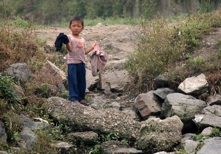 Chlapec nese oblečení ve městě Sinujiu na severokorejské straně řeky Ja-lu, která odděluje Severní Koreu od Číny | Foto: REUTERS / Reinhard Krause