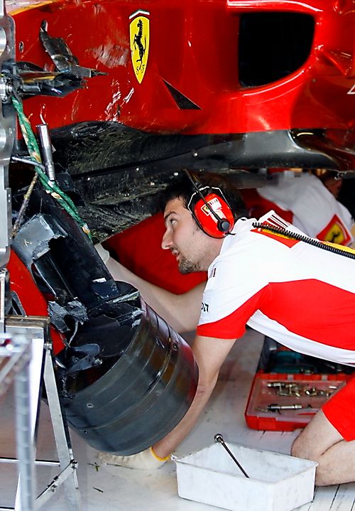 Mechanici prohlížejí rozbité Ferrari Kimi Räikkönena, který v Monze havaroval v sobotním ranním tréninku. | Foto: Reuters