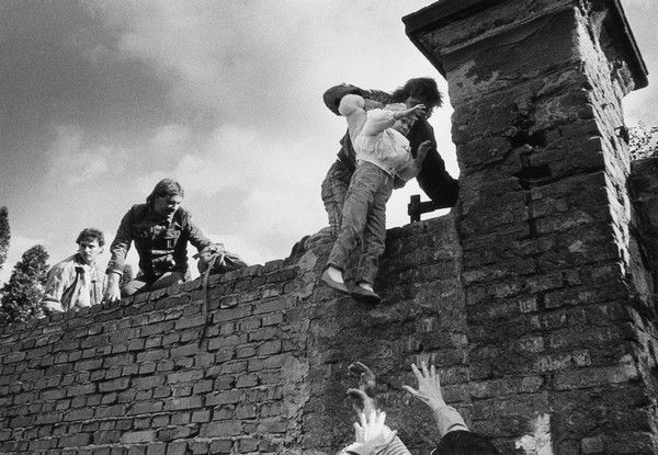 Někteří z uprchlíků nečekají, jak dopadnou jednání politiků, a zeď západoněmeckého velvyslanectví berou útokem | Foto: Karel Cudlín