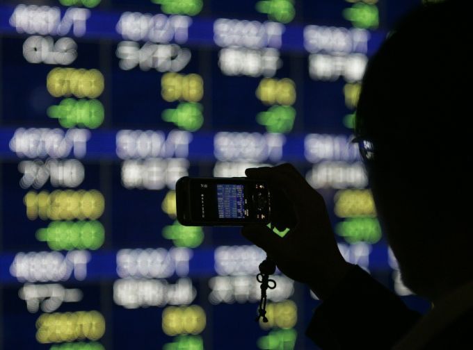 Muž si pořizuje fotografii "nevídaného úkazu" na panelu na burze v Tokiu. Japonský index Nikkei klesl 8. října o 9,4 %, nejvíce od roku 1987 | Foto: Reuters