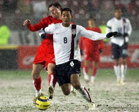 Američan Clint Dempsey (v bílém) bojuje o míč s Jackem Krzynowekem z Polska. | Foto: Reuters