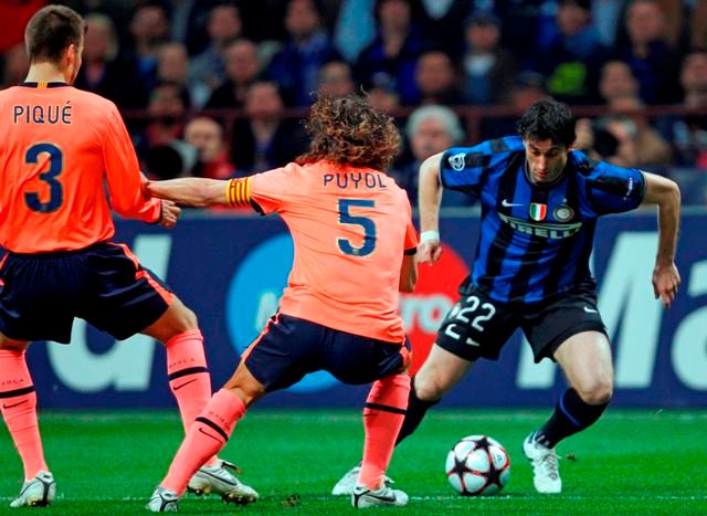 Domácí Diego Milito v souboji s Carlosem Puyolem. | Foto: Reuters