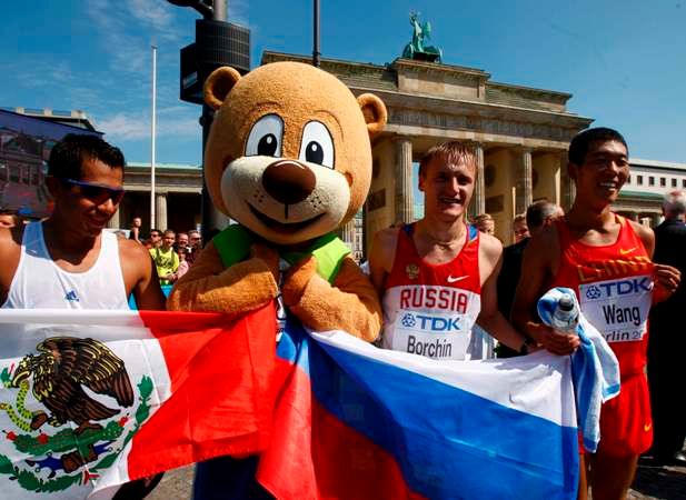 Nejrychleší chodci na 20 km na MS v Berlíně Jesus Sanchez z Mexika (clevo) Wang Hao z Číny a Valerij Borchin půzují s maskotem šampionátu. | Foto: Reuters