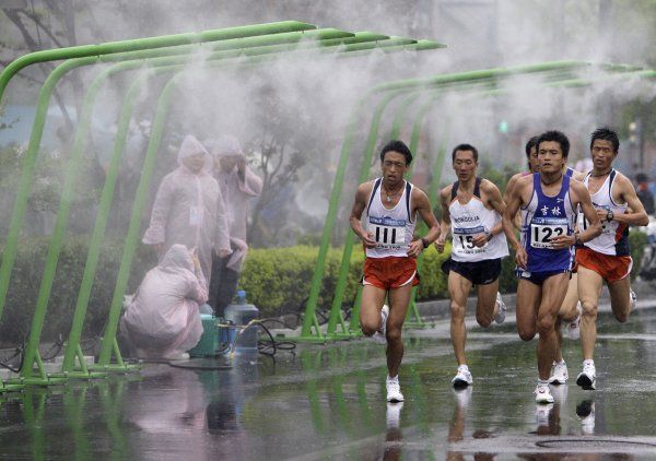 Aby nebylo málo vody. Testovací maraton se běžel za hustého deště, vodní rozprašovače přesto běžely naplno. | Foto: Reuters