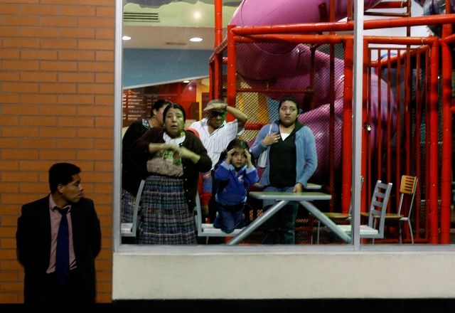 Lidé zírají z fast foodu na místo, kde byl v Ciudad de Guatemala zastřelen řidič autobusu, 23. 10. 2009. | Foto: Reuters