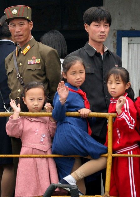 Muži a malé pionýrky na severokorejské vyhlídkové lodi, která se plavila po řece Ja-lu, která odděluje Severní Koreu od Číny | Foto: REUTERS / Reinhard Krause