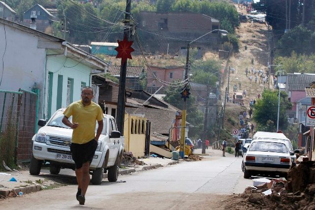 Lidé utíkají na výše položená místa ve městě Constitución poté, co vydaly úřady varování před tsunami. | Foto: Reuters