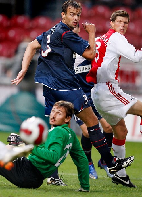 Slávisté Martin Vaniak a Erich Brabec (uprostřed) se dívají na míč vystřelený hráčem Ajaxu Klaasem Janem Huntelaarem. | Foto: Reuters