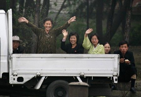 Lidé mávají na fotografa ve městě Sinujiu na severokorejské straně řeky Ja-lu, která odděluje Severní Koreu od Číny | Foto: REUTERS / Reinhard Krause