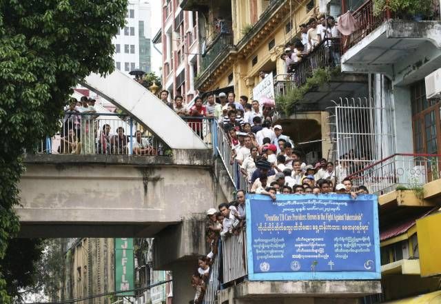 Lidé se shlukují u chrámu: Na tomto snímku z centra Rangúnu sledují modlící se mnichy. | Foto: Reuters