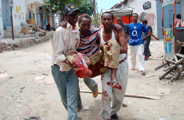 Somálští muži přenášejí zraněného po útoku na tržiště Bakara v Mogadišu | Foto: Reuters