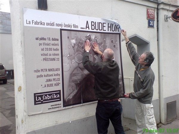 A bude hůř - režisér filmu Petr Nikolaev vyvěšuje spolu se střihačem Jiřím Brožkem plakát na chystané projekce filmu v prostoru La Fabrika | Foto: Aktuálně.cz