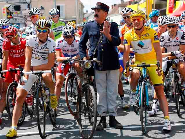 Na startu se chvíli pohyboval i muž na bicyklu, převlečený do tradiční pošťácké uniformy. Etapy se však nezúčastnil. | Foto: Reuters