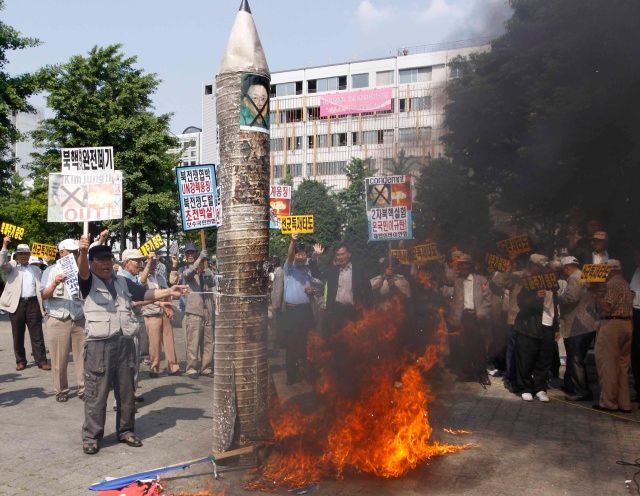 Jihokorejští demonstranti pálí portréty, vlajky a napodobeninu severokorejské rakety, Soul 25. 5. 2009 | Foto: Reuters