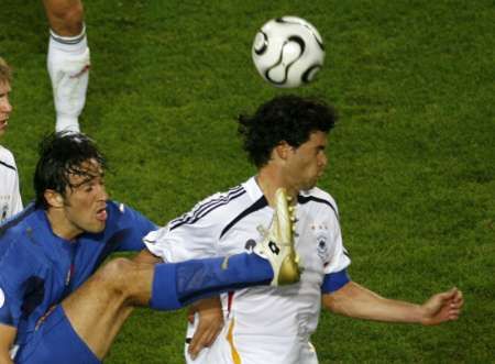 Ital Luca Toni (v modrém) v ostrém souboji s Michaelem Ballackem z Německa. | Foto: Reuters