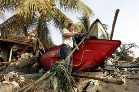 Rybář opatruje loď, poškozenou při tsunami. | Foto: Reuters