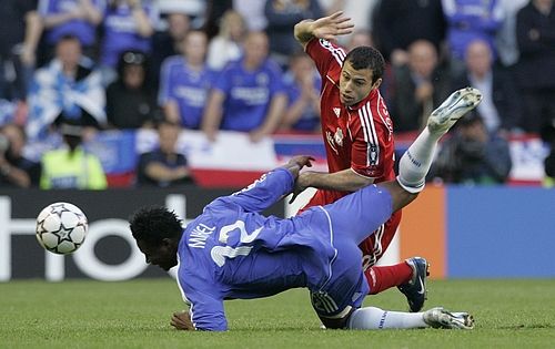 Javier Mascherano z Liverpoolu (v červeném) padá přes hráče Chelsea Johna Obi Mikela. | Foto: Reuters