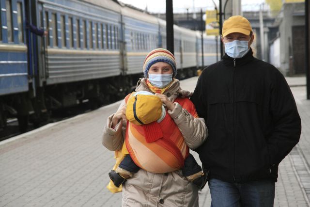 Rodina s rouškami na nádraží v ukrajinském Ternopolu. | Foto: Reuters