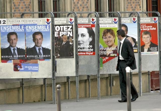 Muž kráčí po ulici v Paříži. Hlavní město Francie je v těchto dnech přímo zaplaveno billboardy prezidentských kandidátů. | Foto: Reuters