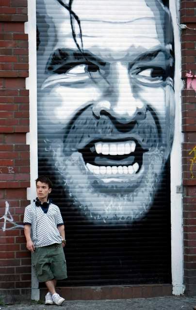 Muž stojící vedle graffiti znázorňujícího Jacka Nicholsona v kultovním filmu Stanleyho Kubricka "Shining" na ulici v Kreuzbergu, 1. května 2009. | Foto: Reuters