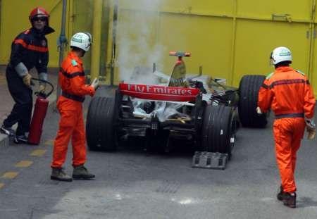 Hasiči kontrolují kouřící McLaren finského pilota Kimi Räikkönena. | Foto: Reuters