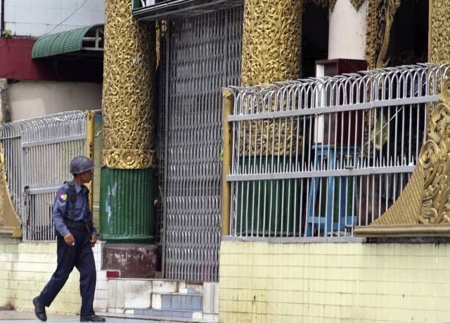 Policista prochází kolem uzamčených vrat jednoho z chrámů v Rangúnu. | Foto: Reuters