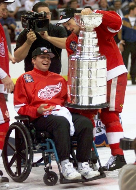 Stanley Cup ale nepíše jen pěkné příběhy. V roce 1997 totiž ruský bek Vladimir Konstantinov, kterému zámořská média kvůli tvrdé hře přezdívala "Vlad nabodávač", při oslavách titulu společně s dalšími spoluhráči havaroval a z nehody si odnesl doživotní následky. Předání Stanley Cupu o rok později z rukou Stevea Yzermana právě Konstantinovovi byla jedna z nejdojemnějších událostí v historii této soutěže. I proto vedení soutěže nechalo jeho jméno zapsat na pohár i v roce 1998, ač za Red Wings neodehrál jediný zápas a na nohy se poprvé postavil až v roce 2013. | Foto: ČTK