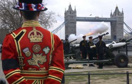 Strážce londýnského královského paláce Tower hledí na nedaleký Tower Bridge. | Foto: Reuters