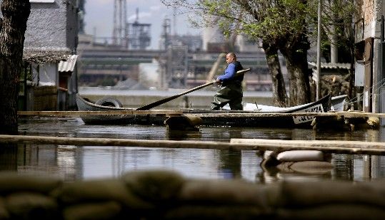 Muž v lodi pluje po zatopené ulici průmyslového města Nikopol na severu Bulharska. | Foto: Reuters