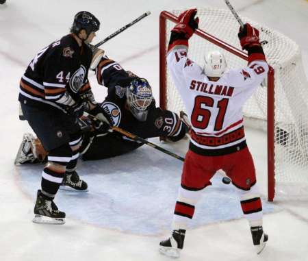 Cory Stillman z Caroliny (v bílém) se raduje z vítězného gólu, který dal jeho spoluhráč Mark Recchi. Puk bezmocně sledují Olejáři Chris Pronger a Jussi Markkanen. | Foto: Reuters