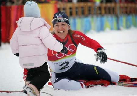 Kateřina Neumannová má zlato. Jako první gratulantka k ní běží dcera Lucie. Turín 2006. | Foto: Reuters