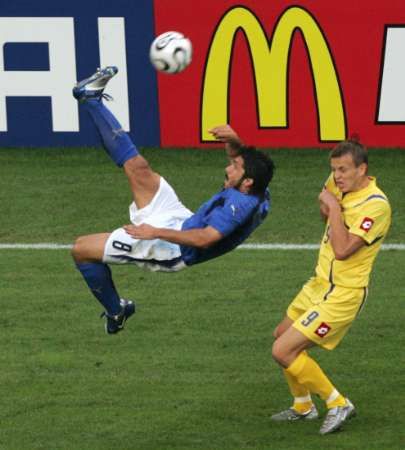 Ital Gennaro Gattuso nůžkami posílá míč z dosahu ukrajinského soupeře Olega Huseva. | Foto: Reuters